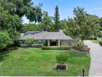 Charming home with lush front lawn, mature trees, and a beautifully landscaped garden, fountain and brick driveway at 103 Greenleaf Ln, Altamonte Springs, FL 32714
