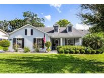 Charming single-story home featuring dormer windows, black shutters, and lush landscaping at 1133 Brandy Lake View Cir, Winter Garden, FL 34787