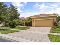 Charming home with a well-manicured lawn, lush landscaping, and a brick driveway at 187 Tall Pines Pass, Kissimmee, FL 34759
