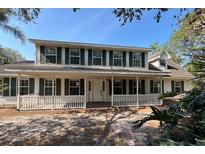 Charming two-story home featuring a welcoming front porch and traditional green shutters, nestled amidst mature trees at 2320 Red Ember Rd, Oviedo, FL 32765