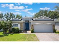 Beautiful one-story home with a blue front door, stone accents and a brick driveway with lovely landscaping at 3436 Gerber Daisy Ln, Oviedo, FL 32766