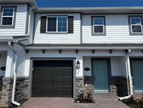 Charming townhouse showcasing a gray garage door, a light blue front door, and stone accents on the lower portion of the facade at 5113 Prairie Preserve Run, St Cloud, FL 34772