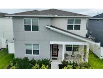 Modern two-story home with a gray exterior, front porch, and well-maintained landscaping at 8563 Compass Point Ave, Orlando, FL 32832