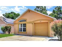 Charming one-story home with tan stucco, arched window, tan garage door, and manicured landscaping at 107 Pamala Ct, Sanford, FL 32771