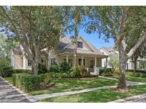 Charming home with a well-manicured lawn, mature trees, and a welcoming front porch at 11415 N Camden Commons Dr, Windermere, FL 34786
