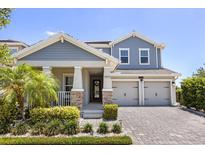 Charming two-story home featuring a well-manicured lawn and a covered front porch with stone supports and a two car garage at 11993 Charades St, Orlando, FL 32832