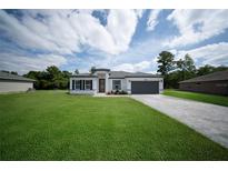 Charming single-Gathering home featuring a well manicured lawn, modern design, and a paved driveway at 13621 Sw 40Th Cir, Ocala, FL 34473