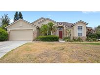 Inviting single-story home with tan exterior, brick accents, and well-maintained landscaping at 144 Henue Ct, Davenport, FL 33896