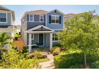 Charming two-story home with blue accents, landscaped yard, and covered front porch entrance at 15959 Pantuso Aly, Winter Garden, FL 34787
