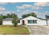 Charming single-story home featuring a red front door, white exterior, and a well-maintained front yard at 205 Sanora Blvd, Sanford, FL 32773