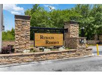 Stone entrance to Rybolt's Reserve community offers a warm welcome with its wood sign and manicured landscaping at 4751 Aguila Pl, Orlando, FL 32826