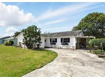Charming single-story home with white exterior, dark shutters, and a spacious front yard at 114 Floral Dr, Kissimmee, FL 34743