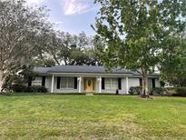 Charming single story home featuring a bright yellow front door, large yard, and mature trees at 1204 Howell Creek Dr, Winter Springs, FL 32708