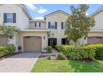 Charming townhouse boasts lush landscaping, a brick walkway, and a convenient two-car garage at 13993 Tarvin St, Orlando, FL 32832