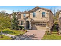 Charming two-story home featuring a brick driveway, neutral stucco siding, and a two-car garage at 1466 Moon Valley Dr, Champions Gate, FL 33896