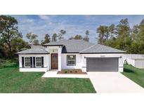 Charming single-story home featuring a gray roof, two-car garage, and a well-manicured lawn at 16600 Sw 23Rd Avenue Rd, Ocala, FL 34473