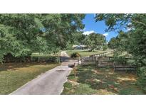 Long, paved driveway leading to a charming home surrounded by mature trees and a wooden fence at 2299 Nw 135Th Ln, Citra, FL 32113