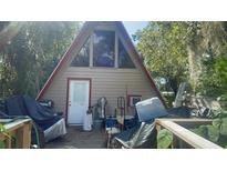A-frame home featuring a red trim, a large window, and a covered deck at 283 Oak Ln, New Smyrna Beach, FL 32168