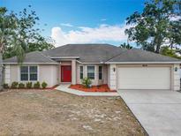 Charming single-story home featuring a red front door, a well-maintained lawn, and an attached two-car garage at 404 Wilshire Dr, Casselberry, FL 32707