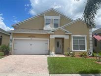 Charming two-story home with a well-maintained lawn, brick paved driveway, and an attached two-car garage at 447 Cadiz Loop, Davenport, FL 33837