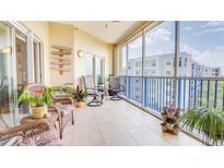 Relaxing screened balcony with seating, tile floor, and coastal-themed decor offers a charming outdoor living space at 5300 S Atlantic Ave # 6-502, New Smyrna Beach, FL 32169