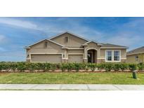 Charming single-story home with a three-car garage, manicured lawn, and stone accents at 7219 Nottingham Reel Ct, St Cloud, FL 34773