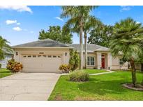 Charming single-story home with a lush lawn, mature palm trees, and a welcoming red front door at 1428 Lucky Pennie Way, Apopka, FL 32712