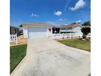 Charming single-story home featuring a well-manicured lawn, white picket fence, and attached garage at 16922 Se 81St Charlesfort Ave, The Villages, FL 32162