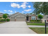 Charming single-story home featuring a manicured lawn, stone accents, and a two-car garage at 217 Victoria Trails Blvd, Deland, FL 32724