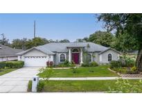 Charming single-story home with a manicured front yard, lush landscaping, and a welcoming red front door at 4265 Conway Place Cir, Orlando, FL 32812