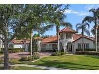 Mediterranean home featuring a terracotta roof, arched entryway, a circular driveway and lush landscaping at 5909 Oxford Moor Blvd, Windermere, FL 34786