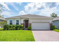 Charming single-story home featuring a well-manicured lawn, brick-accented entryway, and a two-car garage at 1167 Celery Oaks Ln, Sanford, FL 32771