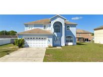 Charming two-story home with a two-car garage, arched entryway, and well-maintained lawn at 1233 Nelson Park Court, Poinciana, FL 34759