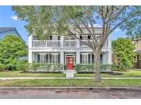 Charming two-story home with a red door, white columns, and a welcoming front porch at 13505 Phoenix Dr, Orlando, FL 32828
