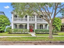 Charming two-story home with a red door, white columns, and a welcoming front porch at 13505 Phoenix Dr, Orlando, FL 32828