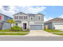 Two-story home with gray siding, stone accents, two car garage, and well-maintained landscaping at 1631 Pontiff Pl, Davenport, FL 33896