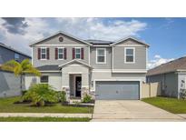 Two-story home with gray siding, stone accents, and a manicured lawn showcasing curb appeal at 1631 Pontiff Pl, Davenport, FL 33896