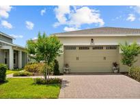 Beige two-car garage door with brick paver driveway and manicured landscaping enhance the curb appeal of this lovely home at 2524 Datura Loop, St Cloud, FL 34772