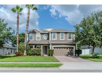 Charming two-story home with a well-manicured lawn, palm trees, and an attached two-car garage at 459 Millwood Pl, Winter Garden, FL 34787