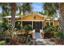 Charming yellow home featuring mature palms, a landscaped front yard, and a welcoming screened-in front porch entrance at 706 Hillcrest St, Orlando, FL 32803