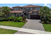 Beautiful two-story home with lush landscaping, brick paved driveway, and a red tile roof at 10819 Savona Way, Orlando, FL 32827