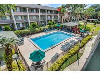 An aerial view of a community pool surrounded by lounge chairs, landscaping, and the exterior of the building at 136 Blue Point Way # 320, Altamonte Springs, FL 32701