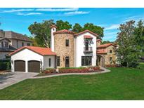 Stunning home featuring a stone turret, red tile roof, and lush, manicured landscaping at 1401 Green Cove Rd, Winter Park, FL 32789