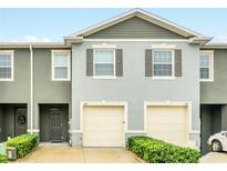 Two-story townhouse with gray facade, two-car garage, and manicured green shrubs at 1401 Yellow Finch Dr, Davenport, FL 33837