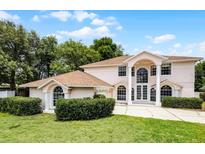 Two-story home featuring a manicured lawn, mature trees, and a circular driveway at 1802 Imperial Palm Dr, Apopka, FL 32712