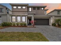 Modern two-story home with a two-car garage, gray driveway, neatly landscaped yard and bushes at 2574 Shanti Dr, Kissimmee, FL 34746