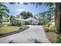 Charming single-story home with lush landscaping, a welcoming driveway, and a delightful light blue front door at 2623 Gables Dr, Eustis, FL 32726