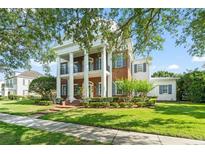 Stately brick home with white columns, black shutters, and lush landscaping at 506 Golfpark Dr, Celebration, FL 34747