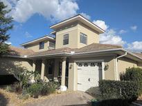 Charming two-story home featuring a barrel tile roof, manicured landscaping, and a brick-paved walkway leading to the entrance at 9104 Stromboli Ct, Kissimmee, FL 34747