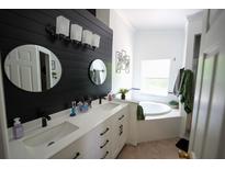 Modern bathroom featuring dual sinks, a soaking tub, and stylish black and white accents at 10255 Cody Ln, Orlando, FL 32825